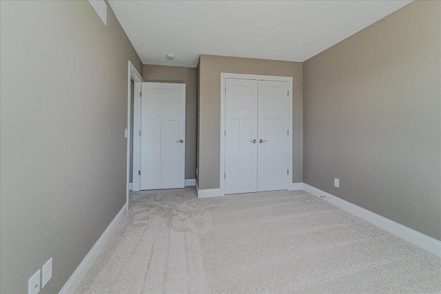 unfurnished bedroom featuring baseboards, light carpet, and a closet