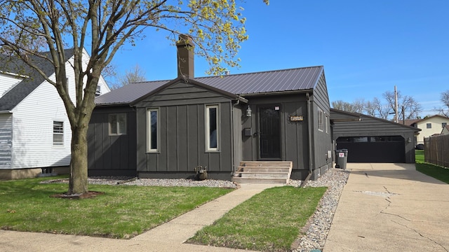 bungalow-style house with board and batten siding, a front yard, a chimney, concrete driveway, and metal roof