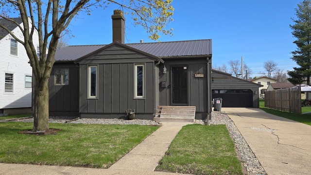 bungalow-style house with board and batten siding, concrete driveway, a front lawn, and metal roof