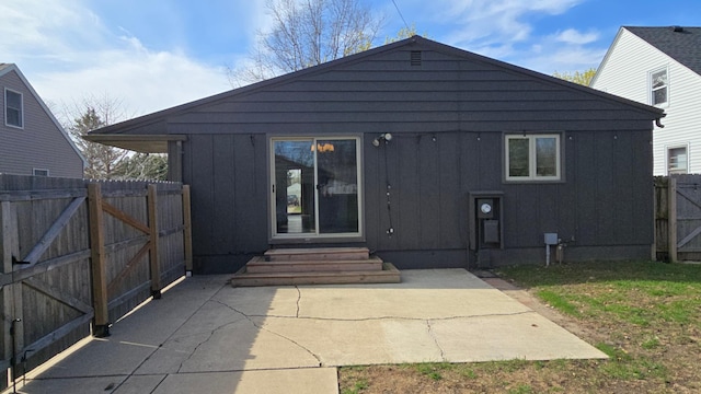 back of house featuring board and batten siding, a gate, fence, a patio, and entry steps