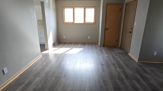 unfurnished bedroom featuring baseboards, visible vents, and dark wood-type flooring