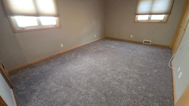 carpeted spare room featuring visible vents and baseboards