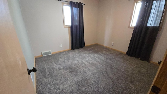 carpeted empty room featuring baseboards and visible vents