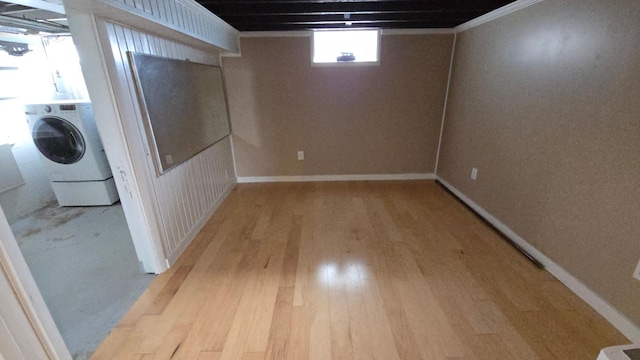 basement featuring baseboards, washer / clothes dryer, and light wood-style flooring