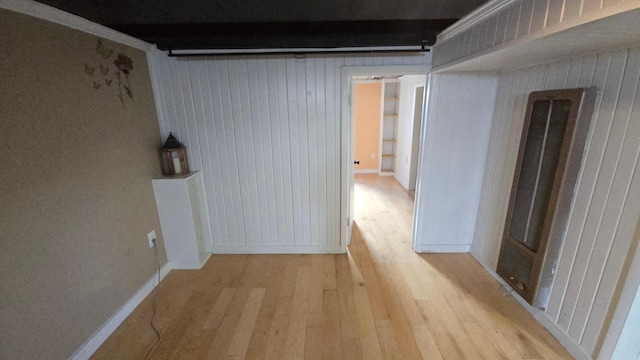 hallway featuring light wood-style floors and wood walls
