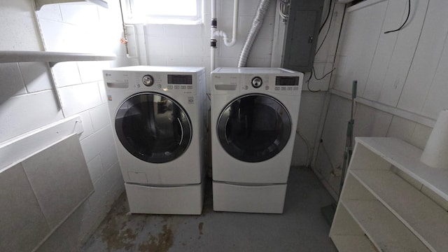 laundry room with laundry area, washer and clothes dryer, electric panel, and concrete block wall