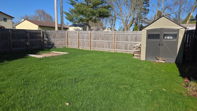 view of yard with a storage unit, a fenced backyard, and an outbuilding