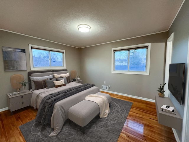 bedroom with baseboards, multiple windows, and wood finished floors