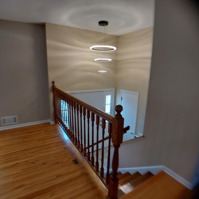 staircase with baseboards, a chandelier, wood finished floors, and visible vents