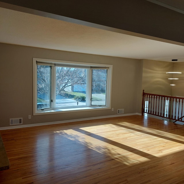 spare room featuring baseboards, wood finished floors, and visible vents