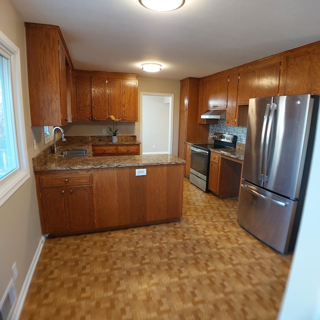kitchen featuring under cabinet range hood, appliances with stainless steel finishes, brown cabinetry, and a sink