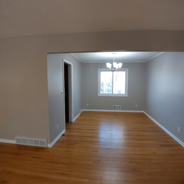 unfurnished room featuring visible vents, light wood-type flooring, baseboards, and an inviting chandelier