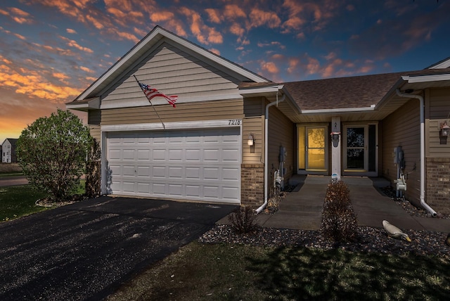 ranch-style home featuring a garage, brick siding, and aphalt driveway