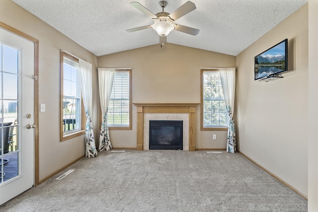 unfurnished living room with a glass covered fireplace, plenty of natural light, vaulted ceiling, and carpet flooring
