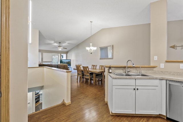 kitchen with white cabinets, a sink, wood finished floors, lofted ceiling, and stainless steel dishwasher