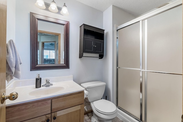 full bathroom with vanity, a textured ceiling, a stall shower, and toilet