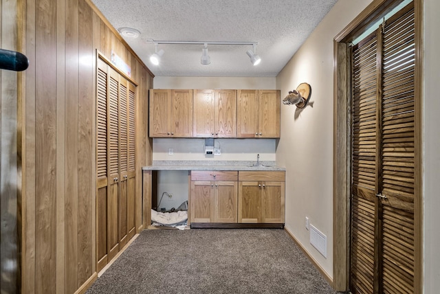 kitchen featuring visible vents, track lighting, dark colored carpet, light countertops, and a sink