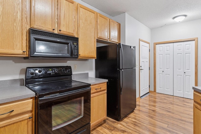 2530 34th St Unit 111, Minneapolis, MN 55406 - kitchen with black appliances, light wood-style flooring, a textured ceiling, light brown cabinetry, and light countertops