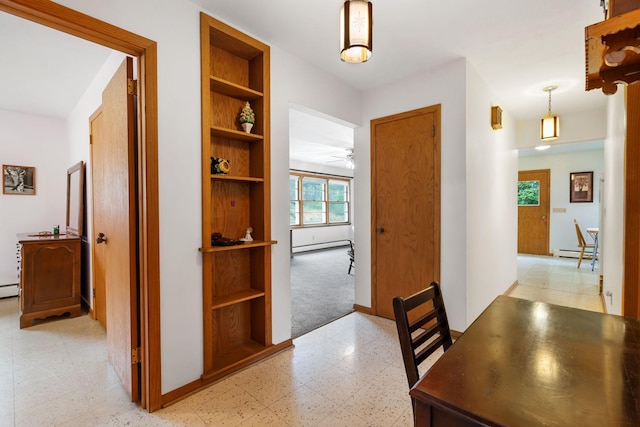 corridor featuring baseboards, a baseboard heating unit, built in features, and light floors