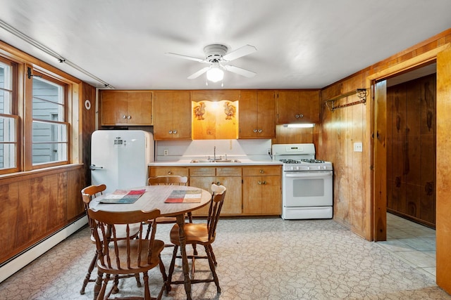 kitchen featuring a sink, baseboard heating, white appliances, and wooden walls