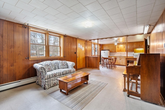 living room featuring light floors, baseboard heating, and wood walls