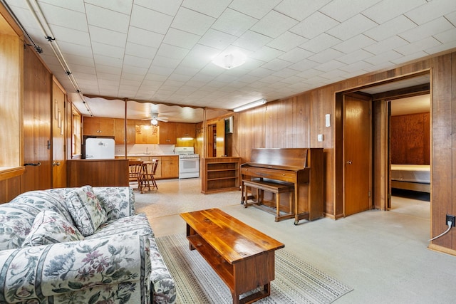 living room with wooden walls, a ceiling fan, and light floors