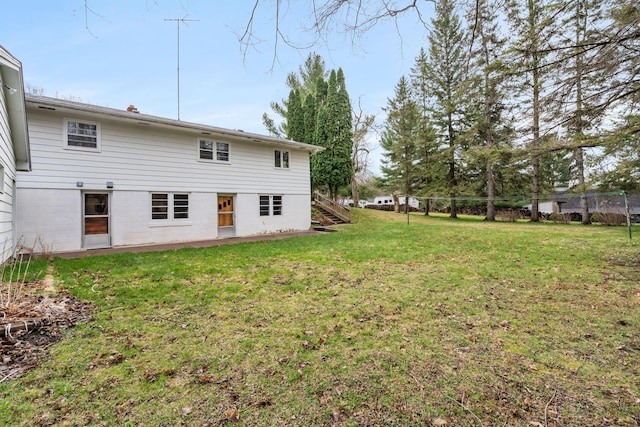 back of house with fence, a yard, and stairway