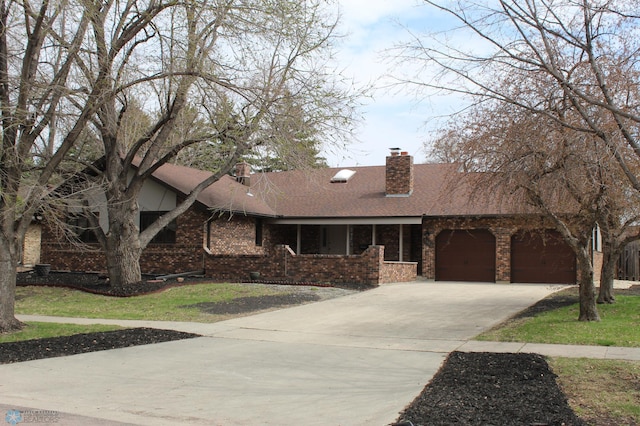 ranch-style home featuring brick siding, a garage, a porch, a chimney, and concrete driveway