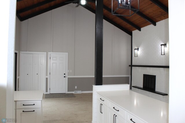 kitchen featuring vaulted ceiling with beams, light wood-style floors, a decorative wall, and wooden ceiling