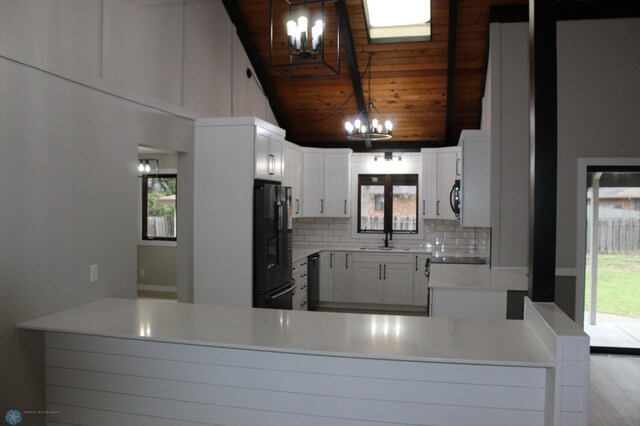 kitchen featuring tasteful backsplash, black fridge with ice dispenser, a sink, wooden ceiling, and a notable chandelier