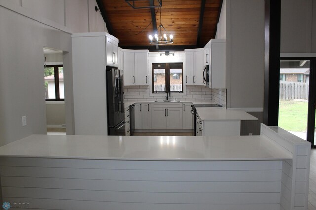 kitchen featuring a sink, a chandelier, electric stove, freestanding refrigerator, and wooden ceiling