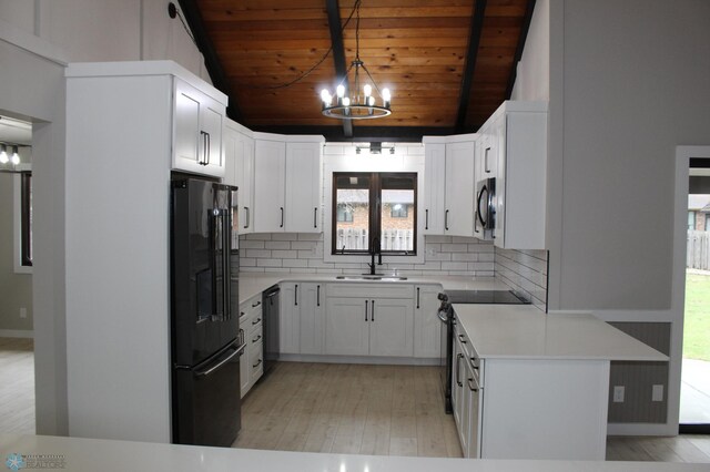 kitchen featuring light countertops, a chandelier, a sink, backsplash, and black appliances
