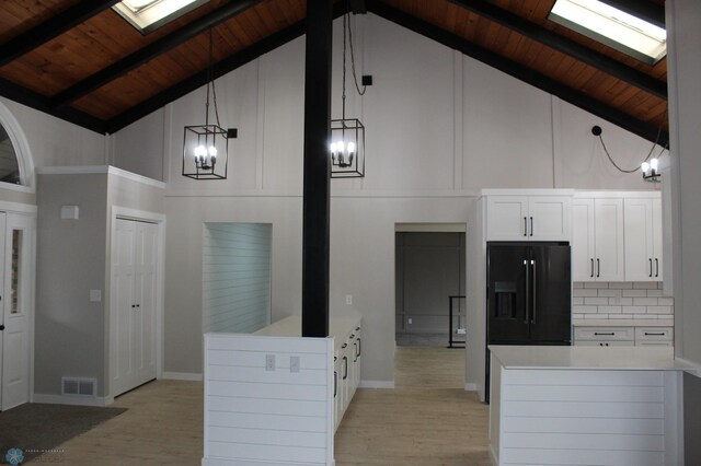 kitchen with visible vents, wooden ceiling, high vaulted ceiling, a chandelier, and black fridge