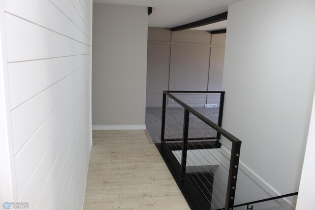 hall featuring baseboards, wood finished floors, and an upstairs landing