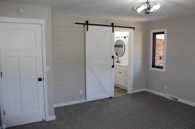 foyer with visible vents, a barn door, baseboards, and dark colored carpet