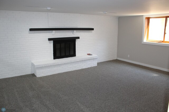 unfurnished living room featuring carpet floors, baseboards, brick wall, and a fireplace