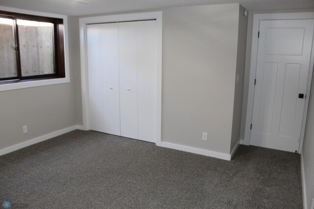 unfurnished bedroom featuring baseboards, carpet, and a closet