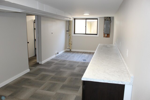 hall with baseboards, electric panel, and dark colored carpet