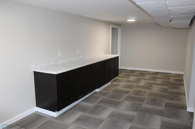 interior space with light countertops, dark cabinets, and baseboards