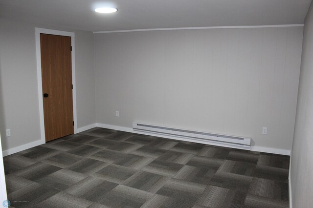 empty room featuring baseboards, dark carpet, and a baseboard heating unit