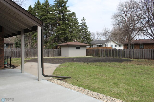 view of yard with an outdoor structure, a fenced backyard, a patio area, and a storage unit
