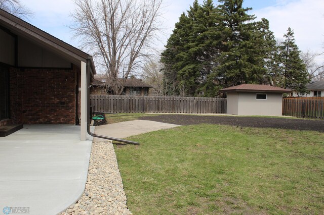 view of yard with a patio, a fenced backyard, and an outbuilding