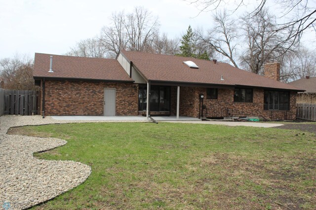back of house with fence, roof with shingles, a chimney, brick siding, and a patio area