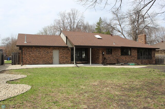 back of house with a yard, brick siding, a chimney, and roof with shingles