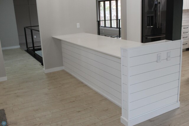 interior space with black refrigerator with ice dispenser and light wood-style floors