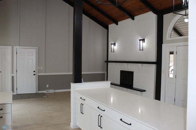 kitchen featuring wood ceiling, light countertops, white cabinets, vaulted ceiling with beams, and light wood-style flooring