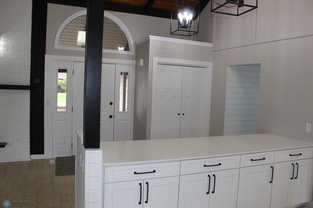 kitchen featuring light countertops, light wood-style flooring, a chandelier, and white cabinets