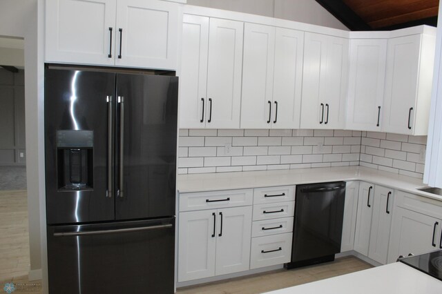 kitchen with lofted ceiling, light countertops, white cabinetry, backsplash, and black appliances