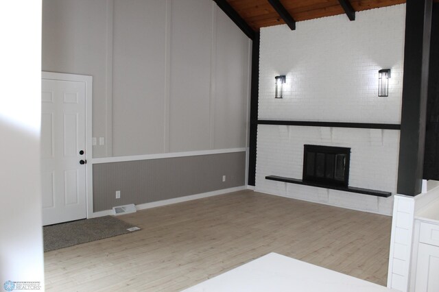 unfurnished living room with visible vents, wood finished floors, a fireplace, vaulted ceiling with beams, and wood ceiling