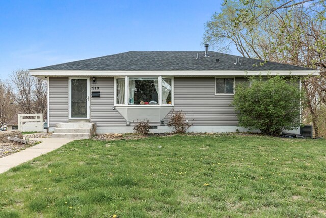 ranch-style home featuring a shingled roof, a front yard, and cooling unit